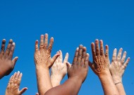 Image of outstreched hands, of different skin colour, against a blue sky