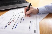 Image of a Gantt chart with hand holding pen making amendments to it
